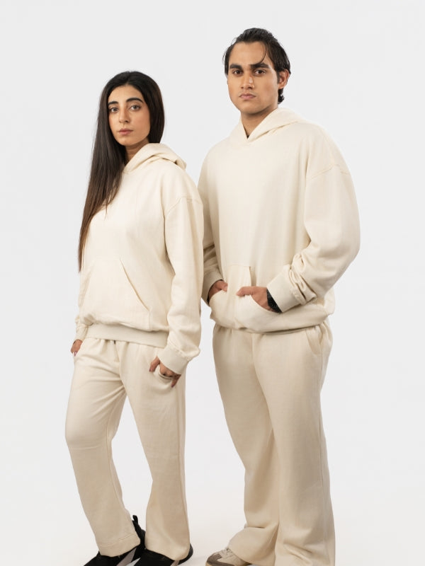 Two people wearing matching cream-colored outfits against a white background