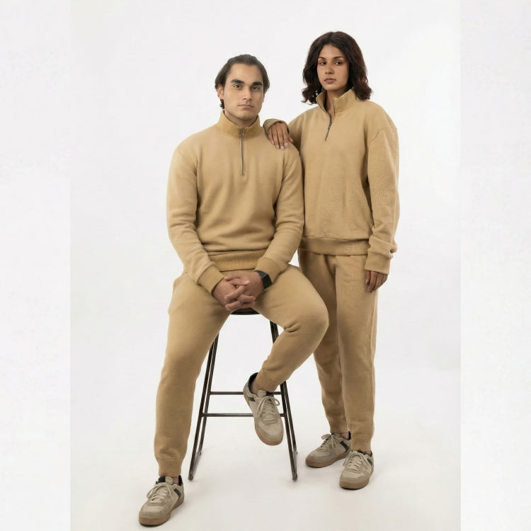 Two people wearing matching beige outfits on a white background