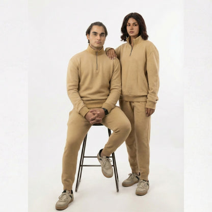 Two people wearing matching beige outfits on a white background