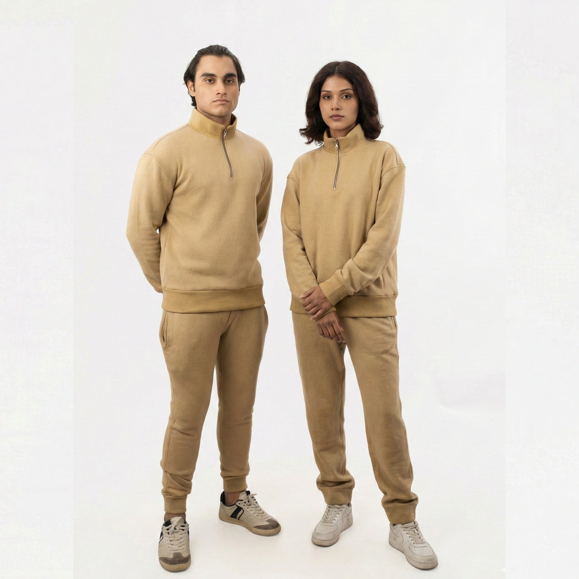Two people wearing matching beige outfits on a white background