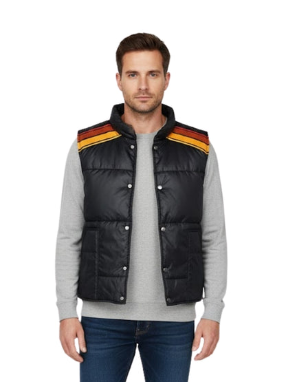 Man wearing a black puffer vest with colorful stripes on a white background
