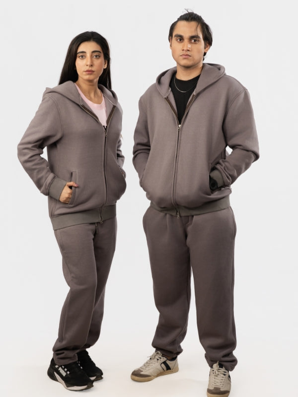 Two people wearing matching gray tracksuits on a white background