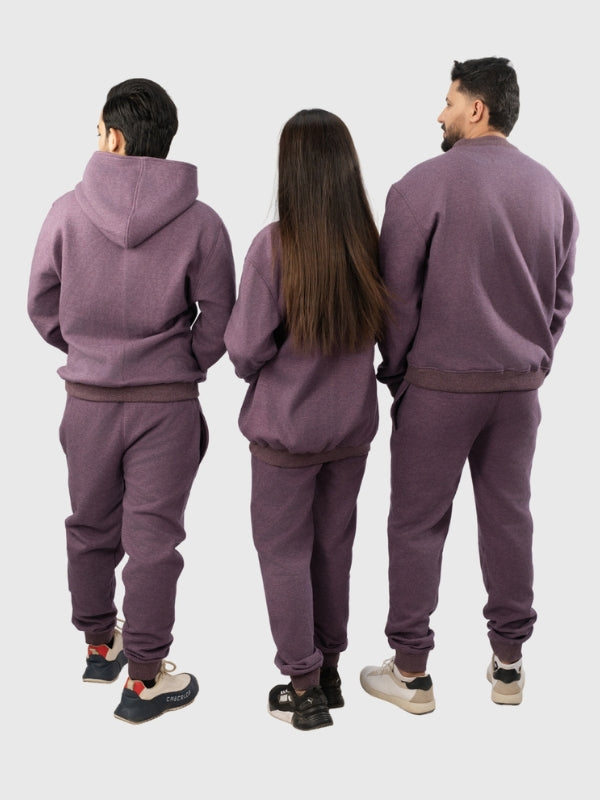Three people wearing matching purple tracksuits from behind on a white background