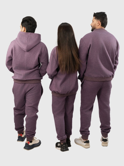 Three people wearing matching purple tracksuits from behind on a white background