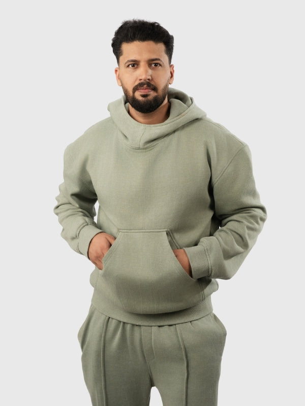 Man wearing a green hoodie and pants on a light gray background