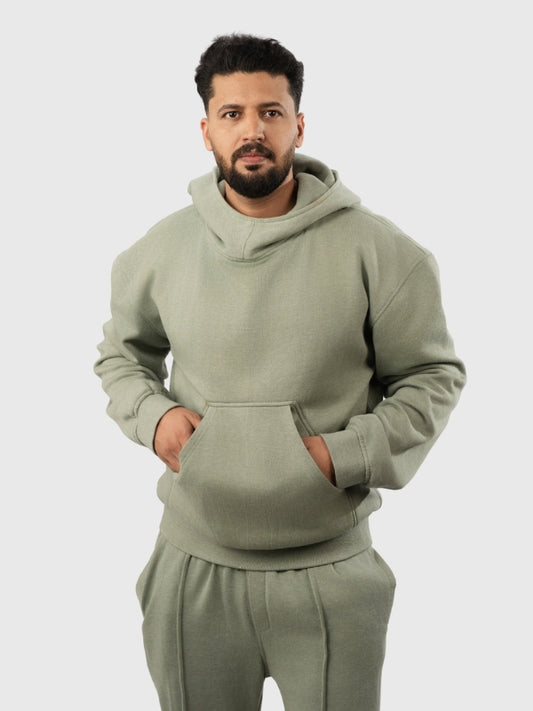 Man wearing a green hoodie and pants on a light gray background
