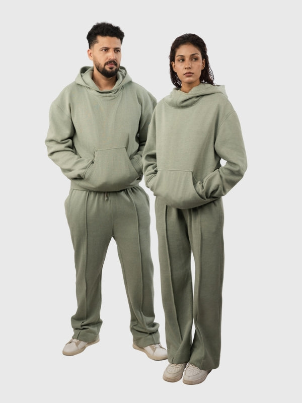 Two people wearing matching olive green hoodies and pants on a white background