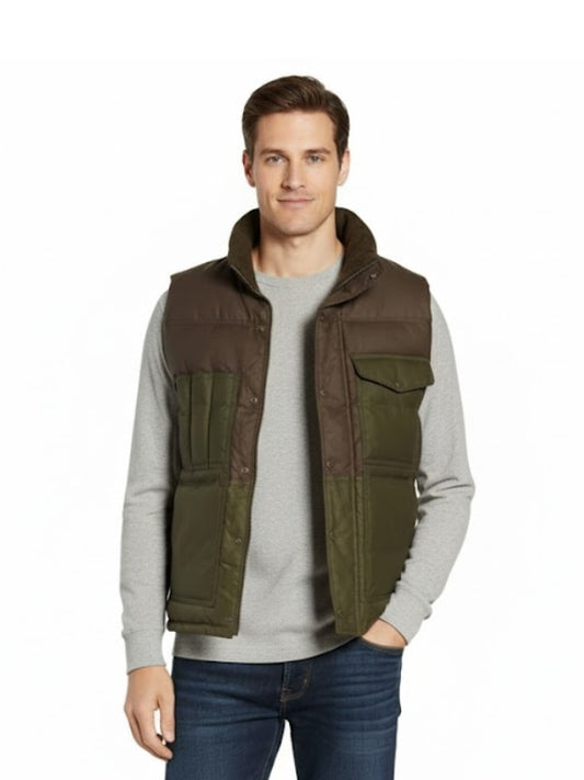 Man wearing a brown and green vest over a gray sweater on a white background