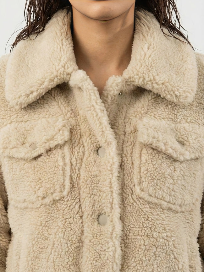 Close-up of a person wearing a beige sherpa jacket.