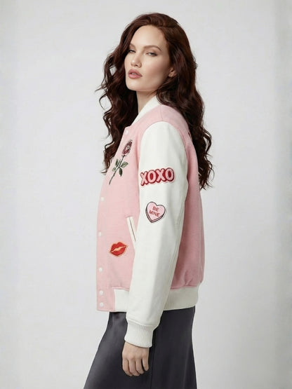 Woman wearing a pink and white varsity jacket with various designs on a plain background