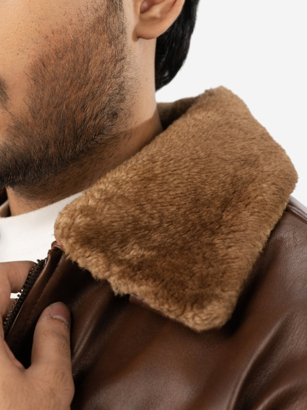 Close-up of a person wearing a brown leather jacket with a fur-lined collar.