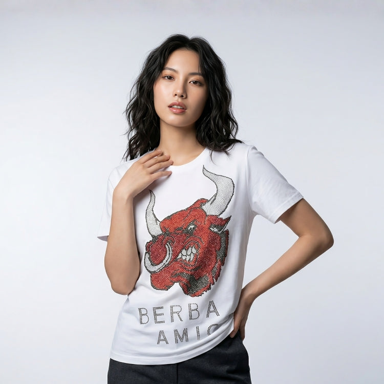 Woman wearing a white t-shirt with a red bull graphic and 'BERBA AMIC' text on a light gray background