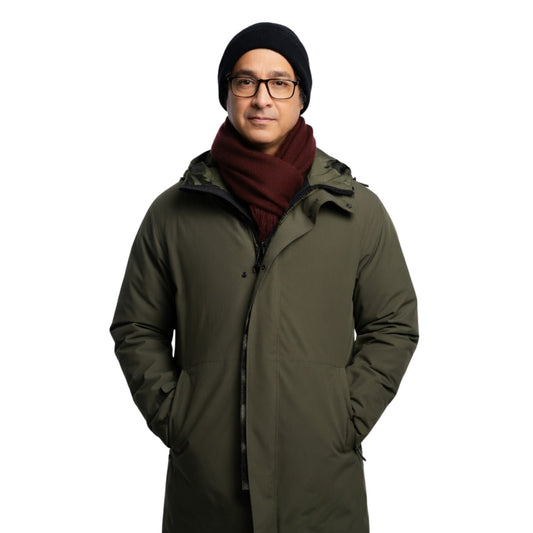Man wearing a long green coat, black beanie, and glasses on a white background