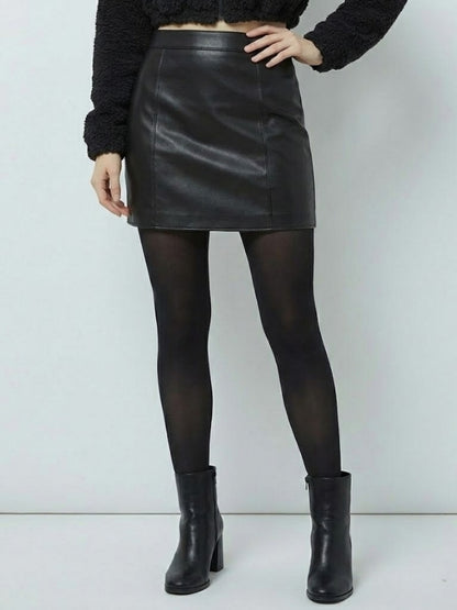 Person wearing a black leather skirt, black tights, and black boots on a white background