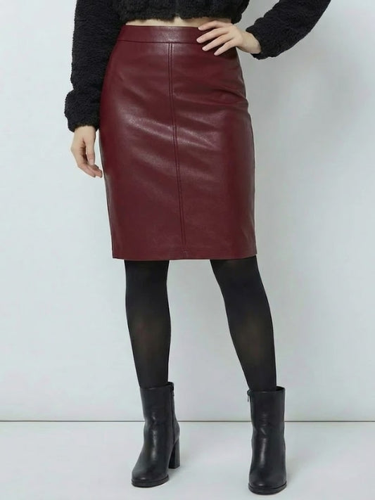 Person wearing a burgundy leather skirt with black tights and boots on a white background