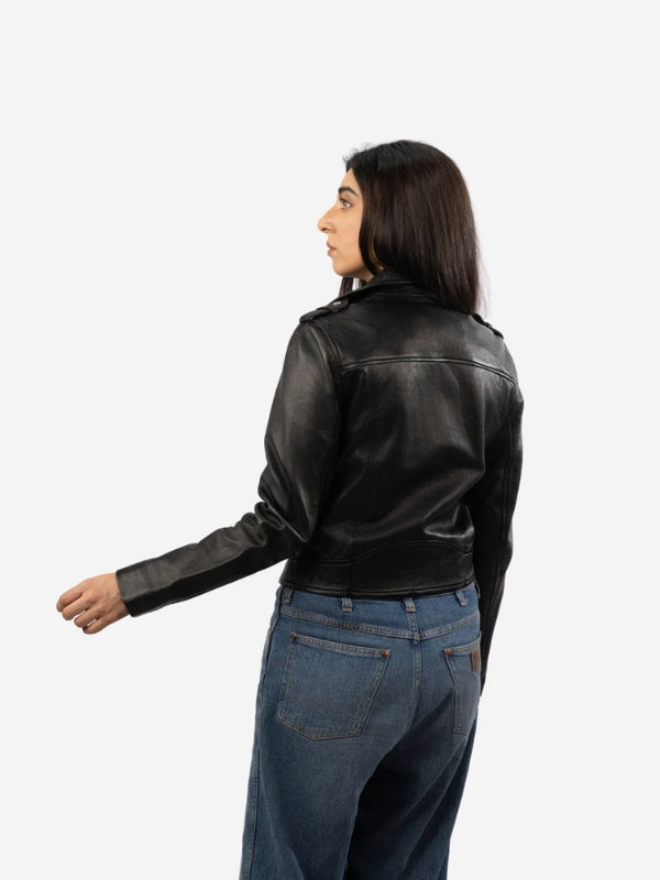 Person wearing a black leather jacket and blue jeans on a white background