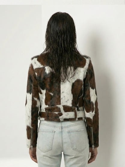 Person wearing a cowhide pattern jacket on a plain background