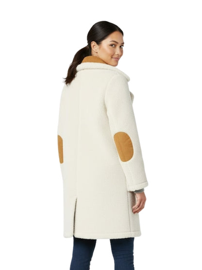 Woman wearing a cream coat with brown patchwork on a white background
