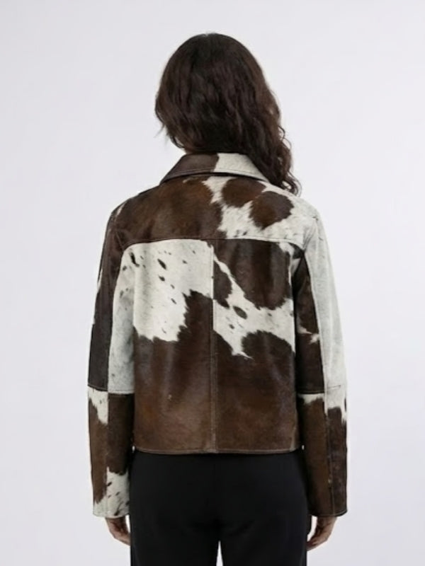 Person wearing a brown and white cowhide jacket on a plain background