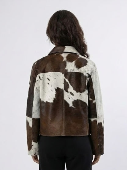 Person wearing a brown and white cowhide jacket on a plain background