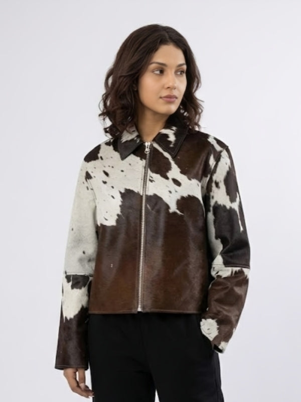 Woman wearing a brown and white cowhide leather jacket on a white background
