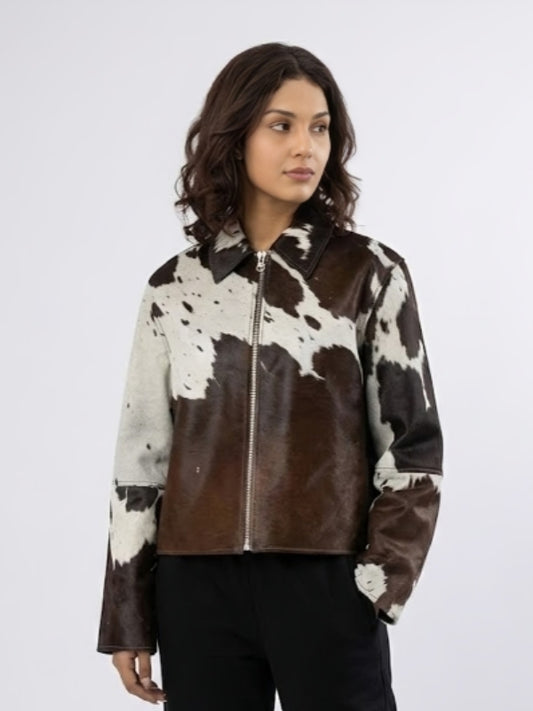 Woman wearing a brown and white cowhide leather jacket on a white background
