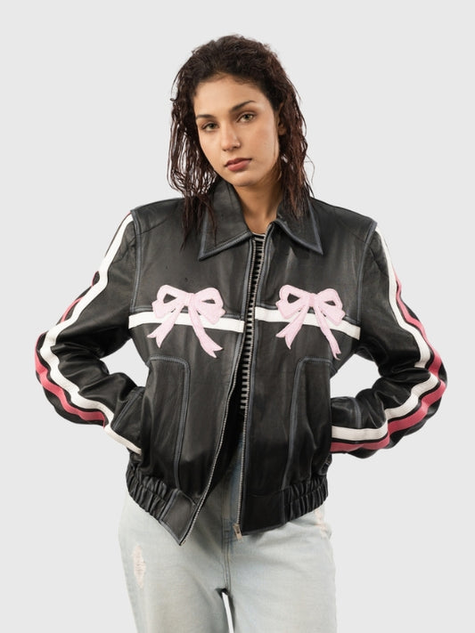 Woman wearing a black leather jacket with pink bows on a light gray background