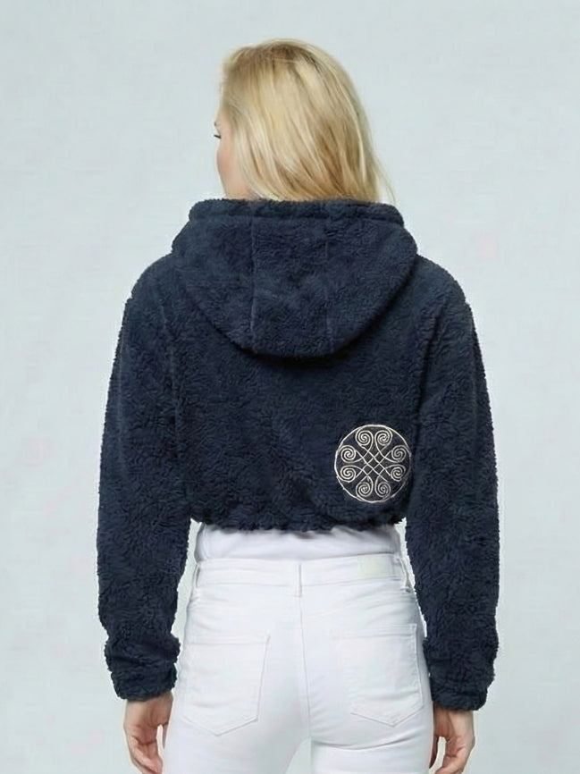 Person wearing a dark blue fleece jacket with a pattern on the back against a light gray background