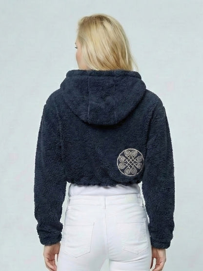 Person wearing a dark blue fleece jacket with a pattern on the back against a light gray background