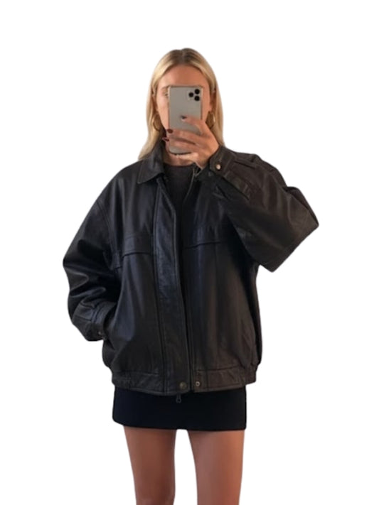 Person wearing a black jacket taking a mirror selfie on a white background
