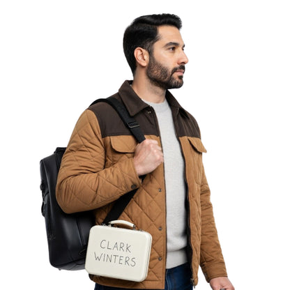 Man holding a black backpack and a white bag with 'Clark Winters' branding on a white background
